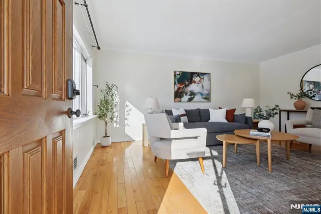 a living room with couches a large mirror and a dining table with wooden floor