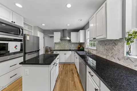 a large kitchen with granite countertop a stove a sink a dining table and chairs