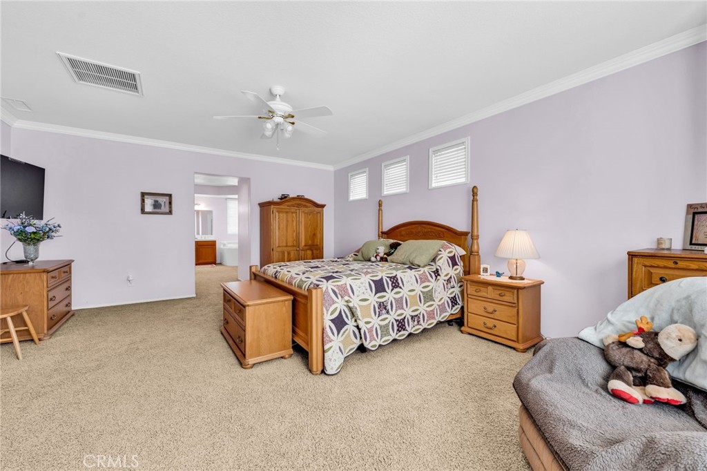 6874 Raspberry Court Eastvale, CA 92880 - Photo 26 of 36 a spacious bedroom with a bed and a chandelier
