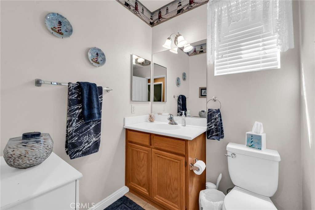6874 Raspberry Court Eastvale, CA 92880 - Photo 27 of 36 a bathroom with a toilet a sink and mirror