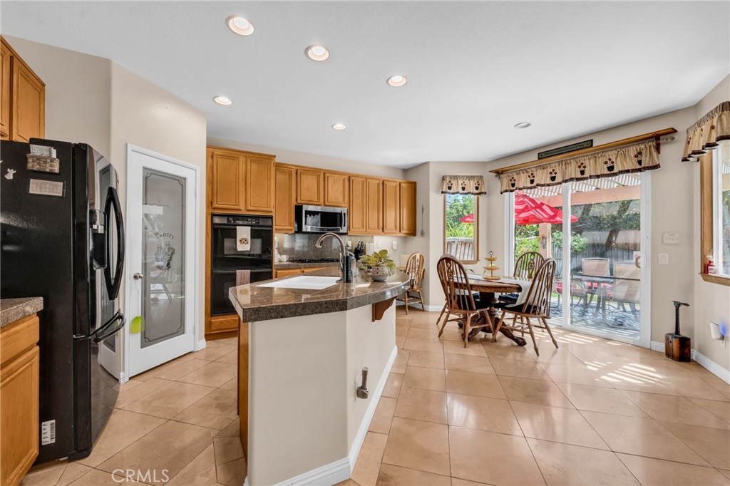 6874 Raspberry Court Eastvale, CA 92880 - Photo 8 of 36 a kitchen with stainless steel appliances kitchen island granite countertop a refrigerator a stove a dining table and chairs with wooden floor
