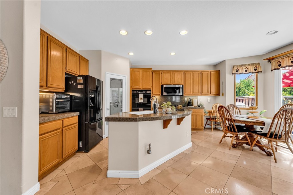 6874 Raspberry Court Eastvale, CA 92880 - Photo 9 of 36 a kitchen with stainless steel appliances kitchen island granite countertop a refrigerator and a stove top oven