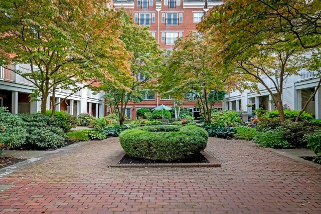 a front view of a building with garden and trees