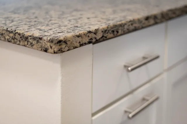 a view of a kitchen with stainless steel appliances granite countertop a refrigerator a stove a sink and a white countertops with wooden floor