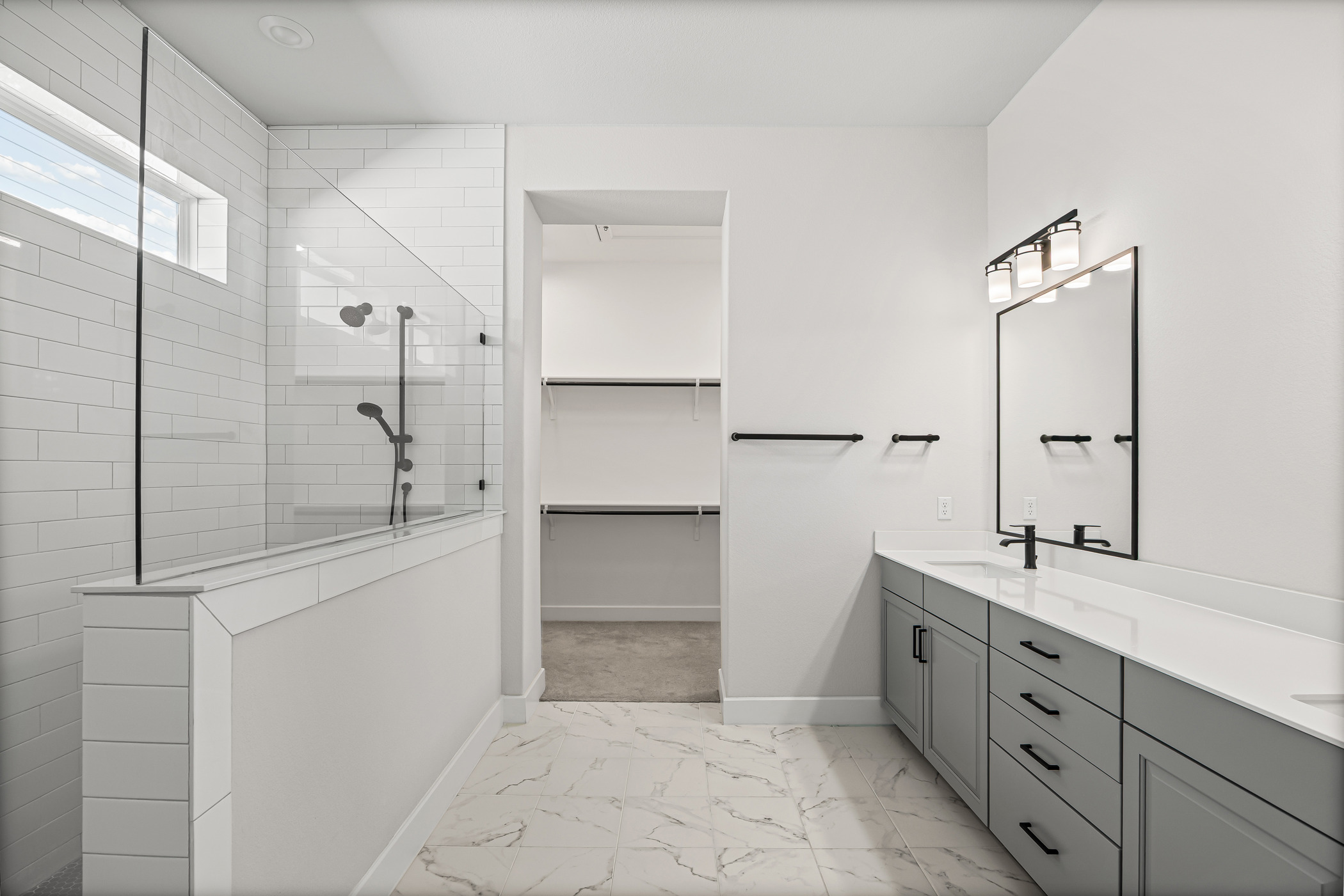 5806 Rangeland Road Austin, TX 78747 - Photo 6 of 34 Modern primary bathroom featuring dual sinks, a spacious walk-in shower, and direct access to a well-organized closet.