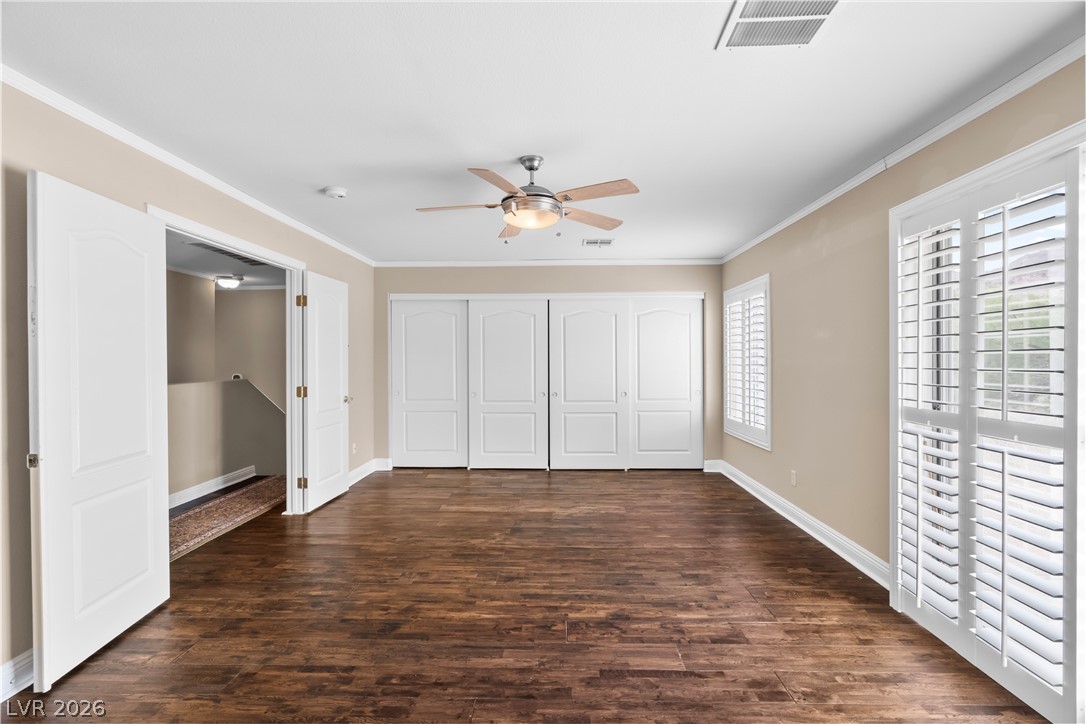 708 Vortex Avenue Henderson, NV 89002 - Photo 29 of 71 Rich hardwood floors complement this spacious primary bedroom with a contemporary ceiling fan and elegant white shutters.