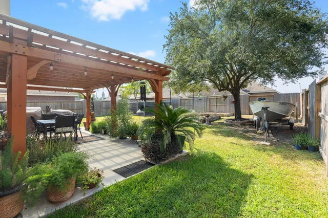 a view of a patio with table and chairs potted plants and large tree
