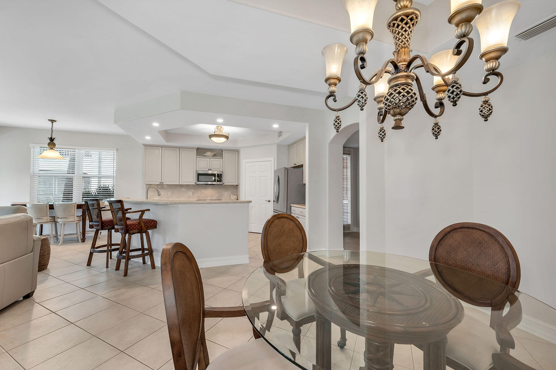 1285 Rialto Way, Unit 102 Naples, FL 34114 - Photo 12 of 49 a kitchen with stainless steel appliances granite countertop a dining table chairs and a chandelier