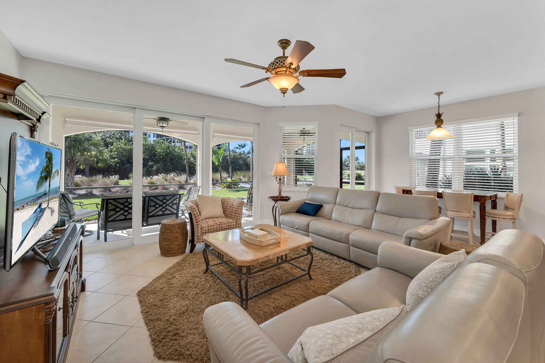 1285 Rialto Way, Unit 102 Naples, FL 34114 - Photo 2 of 49 a living room with furniture a ceiling fan and a flat screen tv