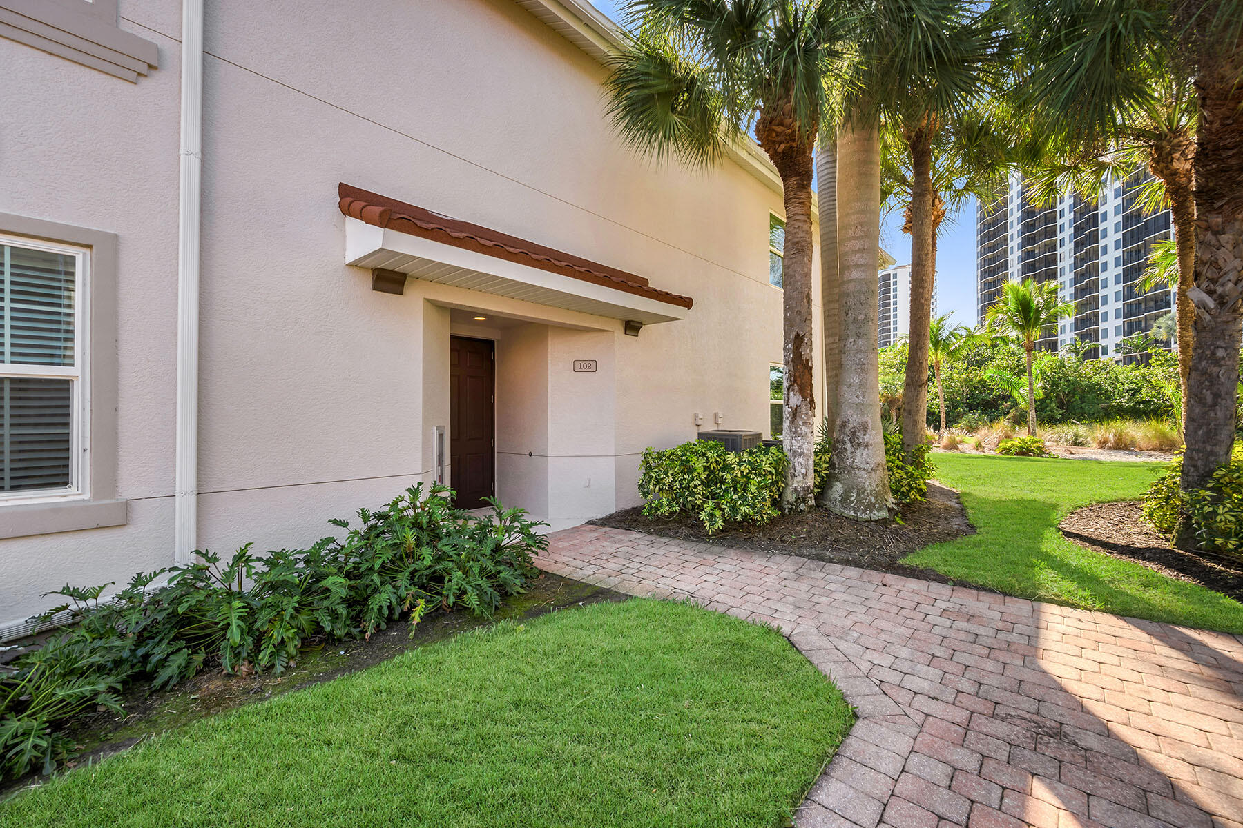 1285 Rialto Way, Unit 102 Naples, FL 34114 - Photo 41 of 49 a view of a house with a small yard and a palm tree