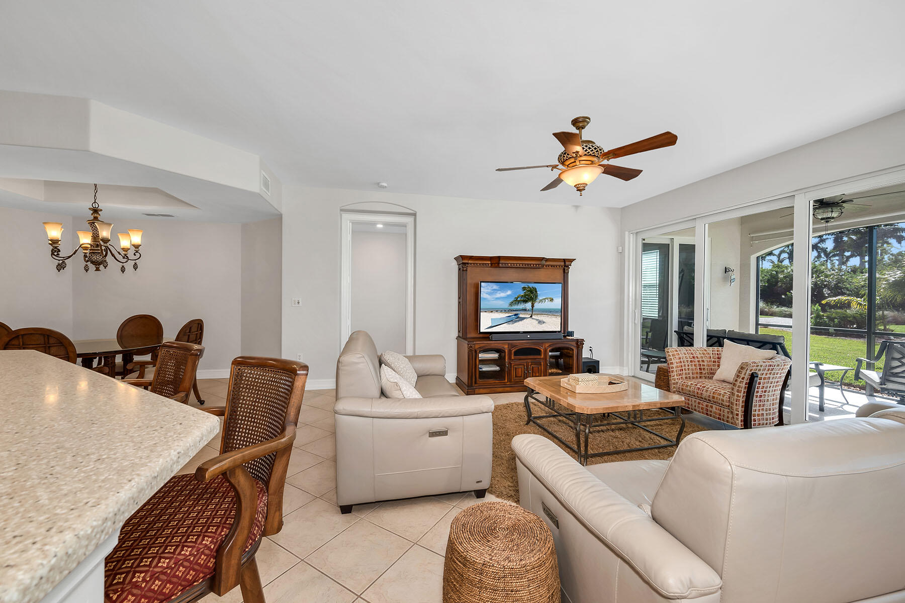 1285 Rialto Way, Unit 102 Naples, FL 34114 - Photo 5 of 49 a living room with furniture a chandelier and a flat screen tv