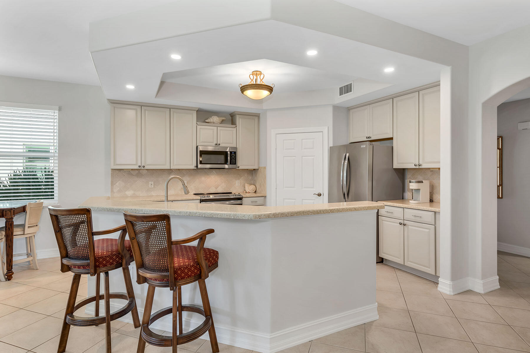 1285 Rialto Way, Unit 102 Naples, FL 34114 - Photo 9 of 49 a kitchen with stainless steel appliances granite countertop a stove a sink a refrigerator and a microwave