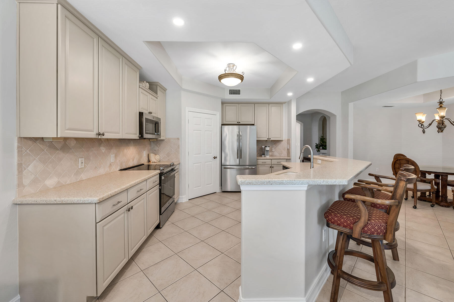1285 Rialto Way, Unit 102 Naples, FL 34114 - Photo 10 of 49 a kitchen with kitchen island granite countertop wooden cabinets and white appliances