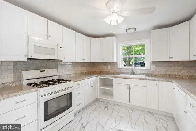a kitchen with granite countertop white cabinets white stainless steel appliances with a sink and dishwasher
