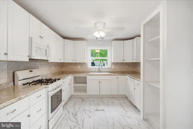 a kitchen with granite countertop a stove a sink and dishwasher a refrigerator with white cabinets