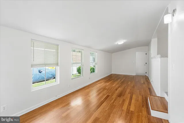 a view of an empty room with wooden floor and windows