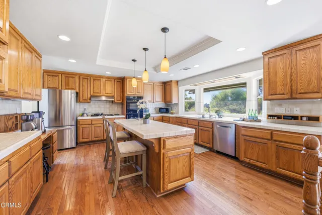 a kitchen with stainless steel appliances kitchen island granite countertop wooden floors and wooden cabinets