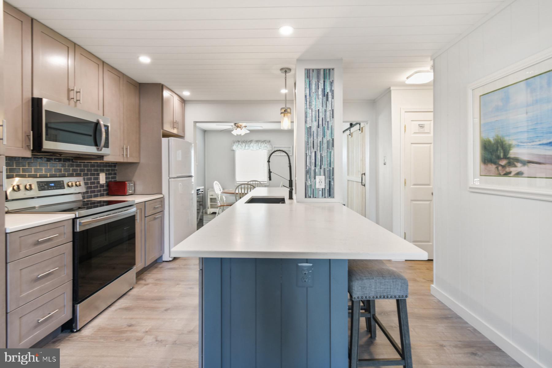 722 Mooring Road, Unit A104 Ocean City, MD 21842 - Photo 11 of 33 a large kitchen with a table chairs stainless steel appliances and cabinets