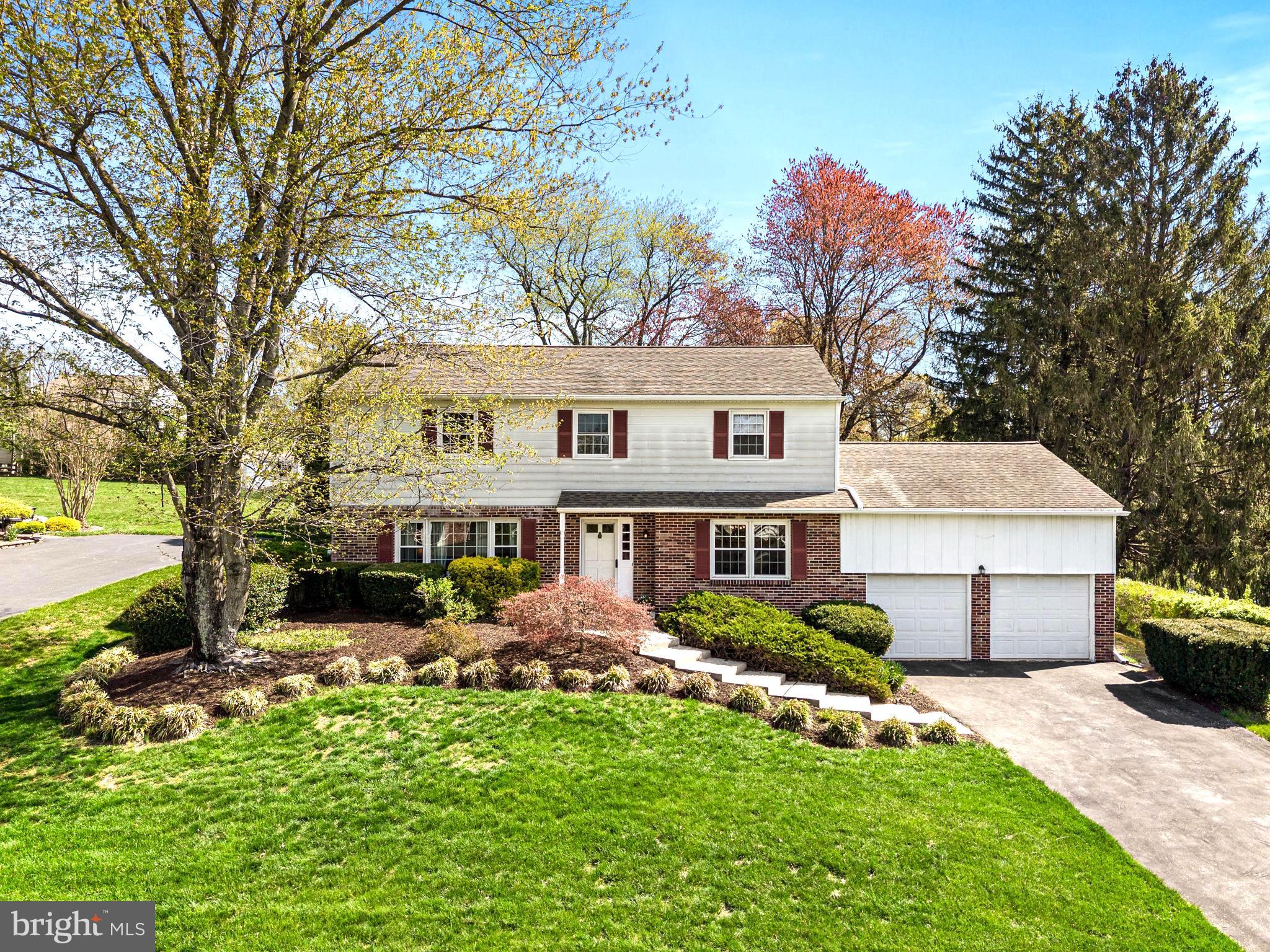 a front view of a house with a garden and trees