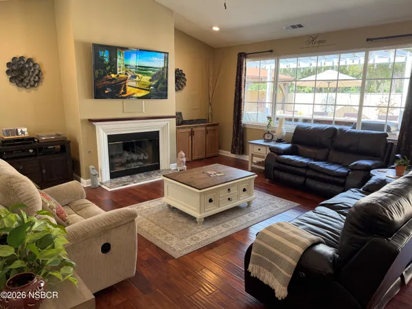 a living room with couches a fireplace with wooden floor