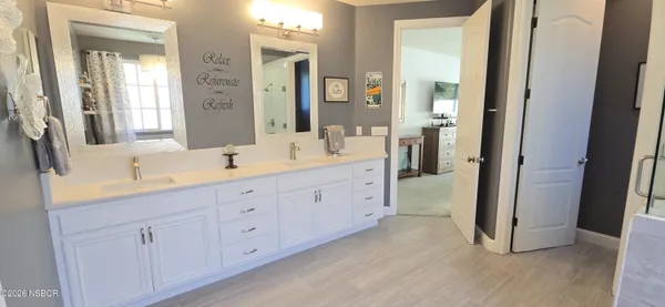 a spacious bathroom with a double vanity sink a mirror a vanity and a bathtub
