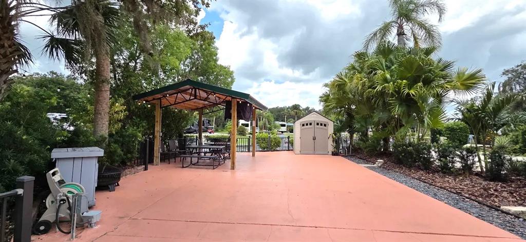 568 Waterway Drive River Ranch, FL 33867 - Photo 4 of 21 a view of a patio with a table and chairs under an umbrella with large trees