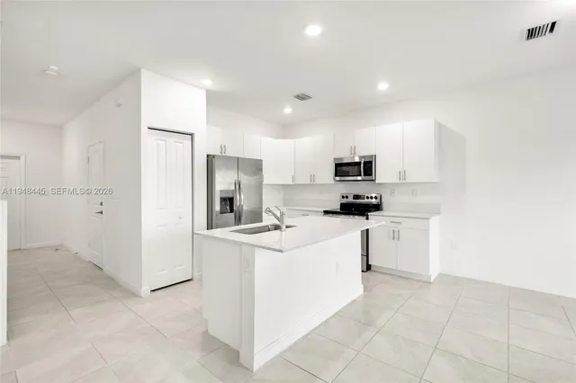a kitchen with stainless steel appliances granite countertop a refrigerator sink and white cabinets