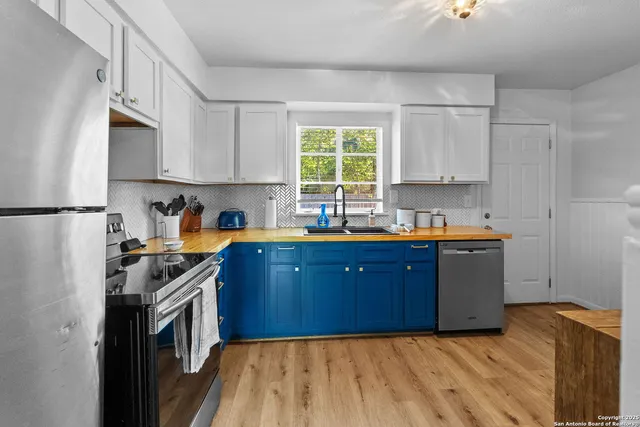 a kitchen with a refrigerator a stove a sink dishwasher and wooden cabinets with wooden floor