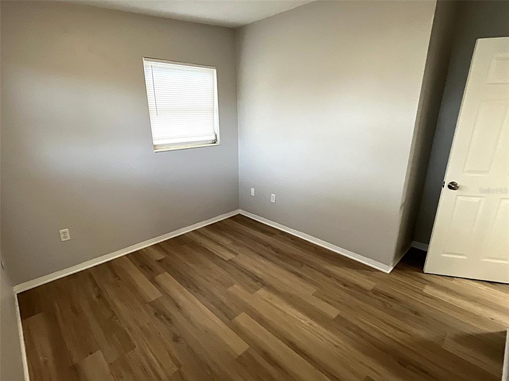 9596 Groveland Street Seminole, FL 33772 - Photo 19 of 26 an empty room with wooden floor and windows