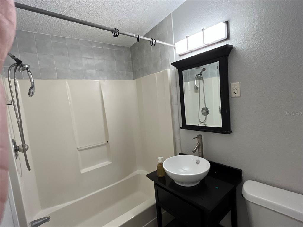 9596 Groveland Street Seminole, FL 33772 - Photo 24 of 26 a bathroom with a granite countertop sink a toilet a shower and a mirror