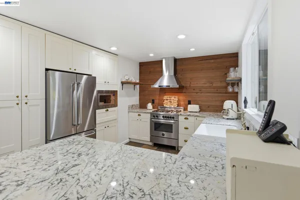 a kitchen with stainless steel appliances kitchen island granite countertop a refrigerator a stove and a sink
