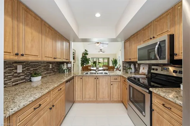 a kitchen with stainless steel appliances granite countertop a stove top oven a sink dishwasher and a microwave oven with white cabinets