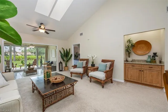a living room with furniture a chandelier fan and a large window