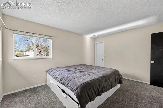 a bed sitting in a spacious bedroom next to a window