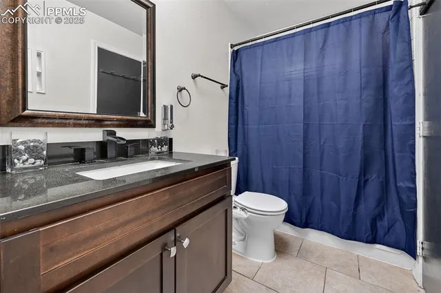 a bathroom with a granite countertop sink toilet and mirror