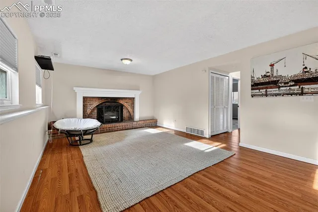 a view of an empty room with window and wooden floor