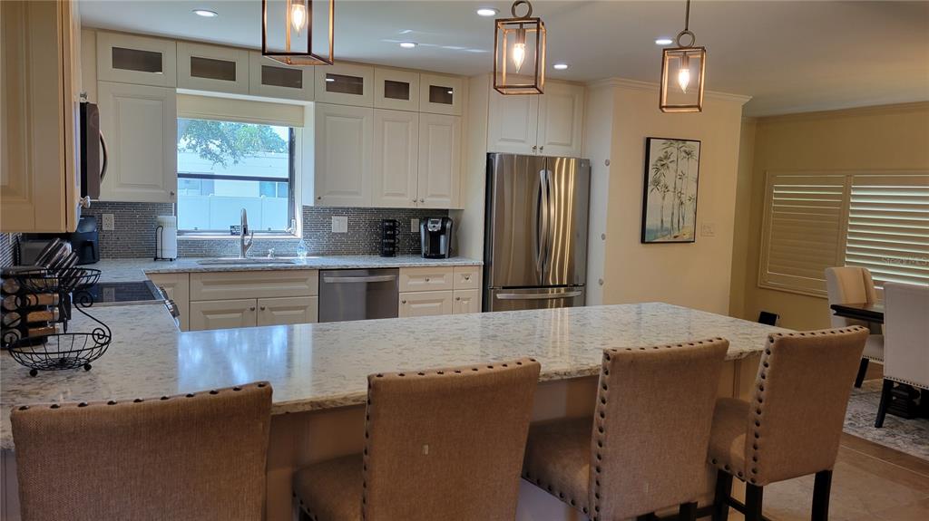 3932 Sunshine Avenue Sarasota, FL 34231 - Photo 4 of 17 a kitchen with stainless steel appliances granite countertop a refrigerator a sink dishwasher a dining table and chairs with wooden floor