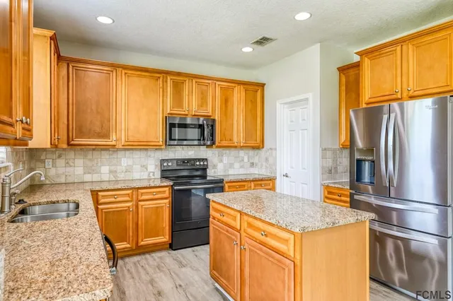 a kitchen with stainless steel appliances granite countertop a refrigerator a stove top oven a sink and dishwasher