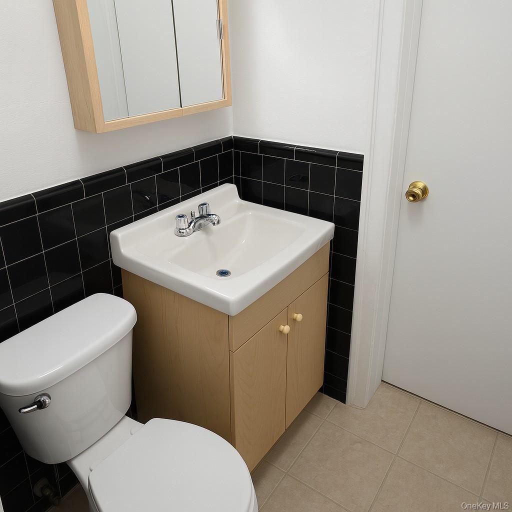 540 East State Street Long Beach, NY 11561 - Photo 8 of 12 Bathroom featuring tile walls, vanity, light tile patterned flooring, and a wainscoted wall