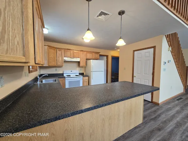 a kitchen with stainless steel appliances granite countertop a refrigerator a sink dishwasher a stove and white countertops with wooden floor