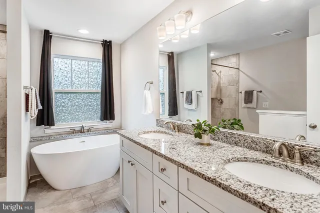 a bathroom with a granite countertop tub sink and mirror