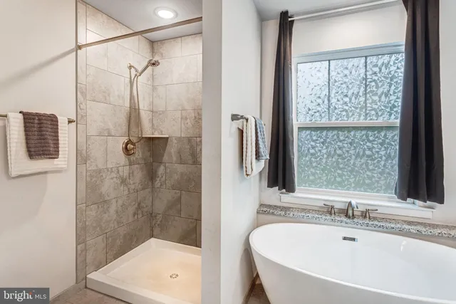 a bathroom with a tub a sink a window and a shower