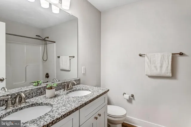 a bathroom with a granite countertop sink toilet a large mirror and shower
