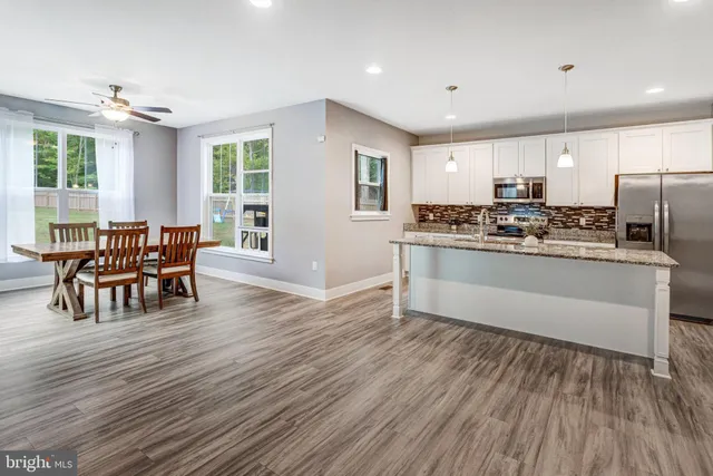a kitchen with stainless steel appliances granite countertop wooden floors and white cabinets