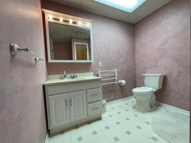 a bathroom with a granite countertop toilet sink and mirror