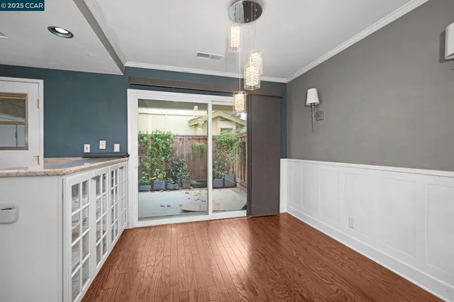 a view of an empty room with wooden floor and windows