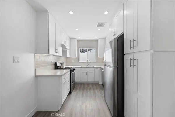 a kitchen with white cabinets and stainless steel appliances