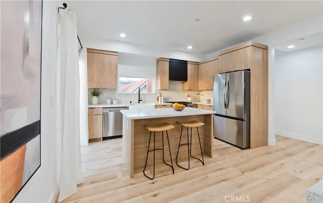 a kitchen with stainless steel appliances a refrigerator a stove a sink dishwasher and a refrigerator with wooden floor