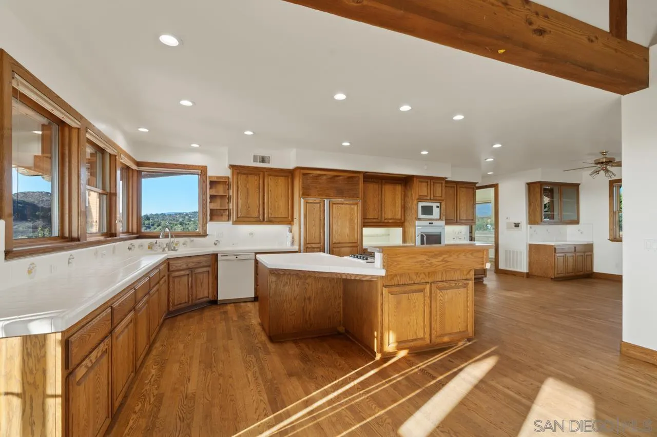 15718 Fruitvale Road Valley Center, CA 92082 - Photo 28 of 49 a large living room with stainless steel appliances kitchen island granite countertop a refrigerator a stove a sink and a dining table with wooden floor
