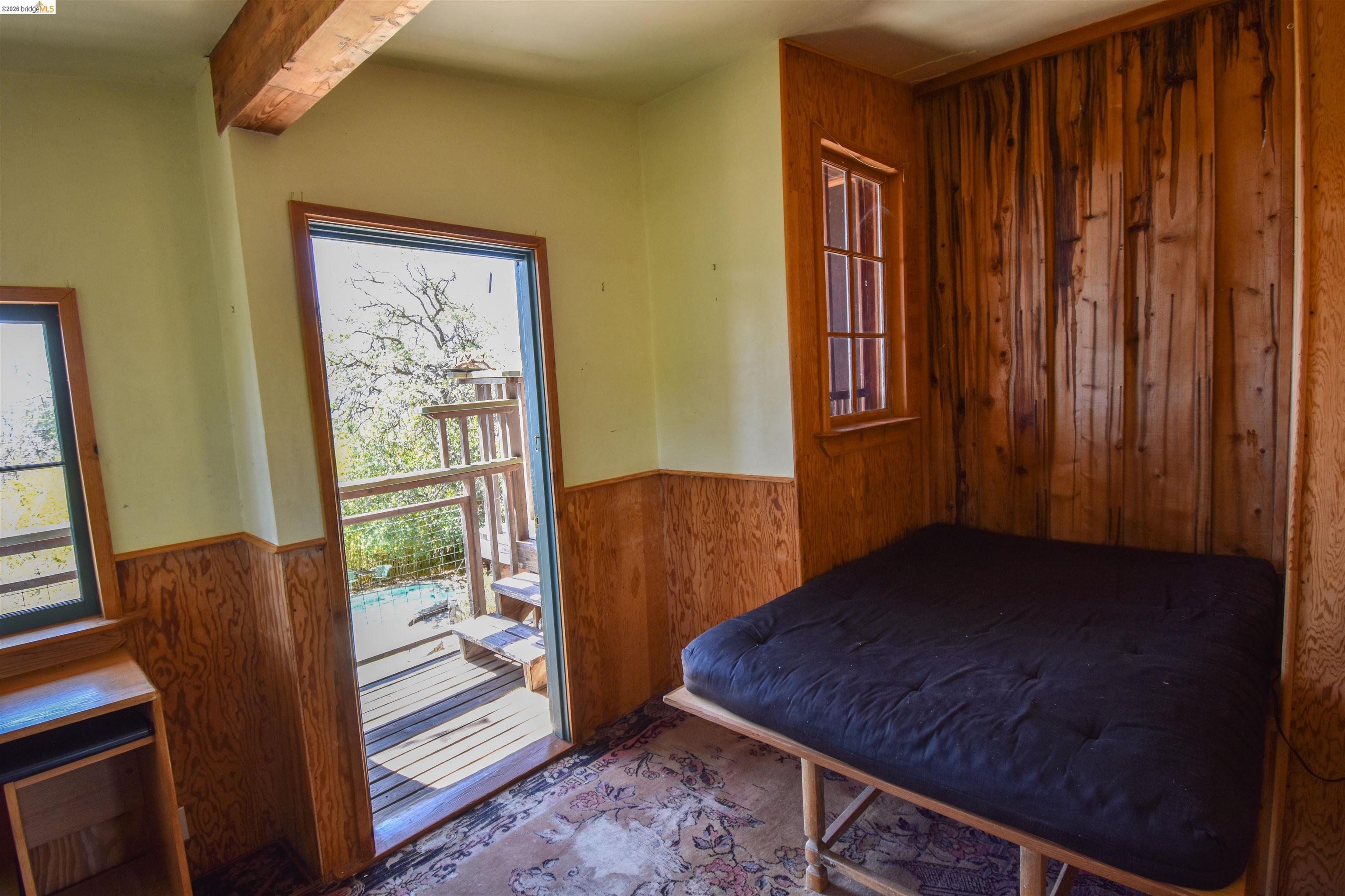 17270 Robin Ridge Road Sonora, CA 95370 - Photo 22 of 60 Bedroom with wooden walls, wainscoting, beamed ceiling, and access to outside